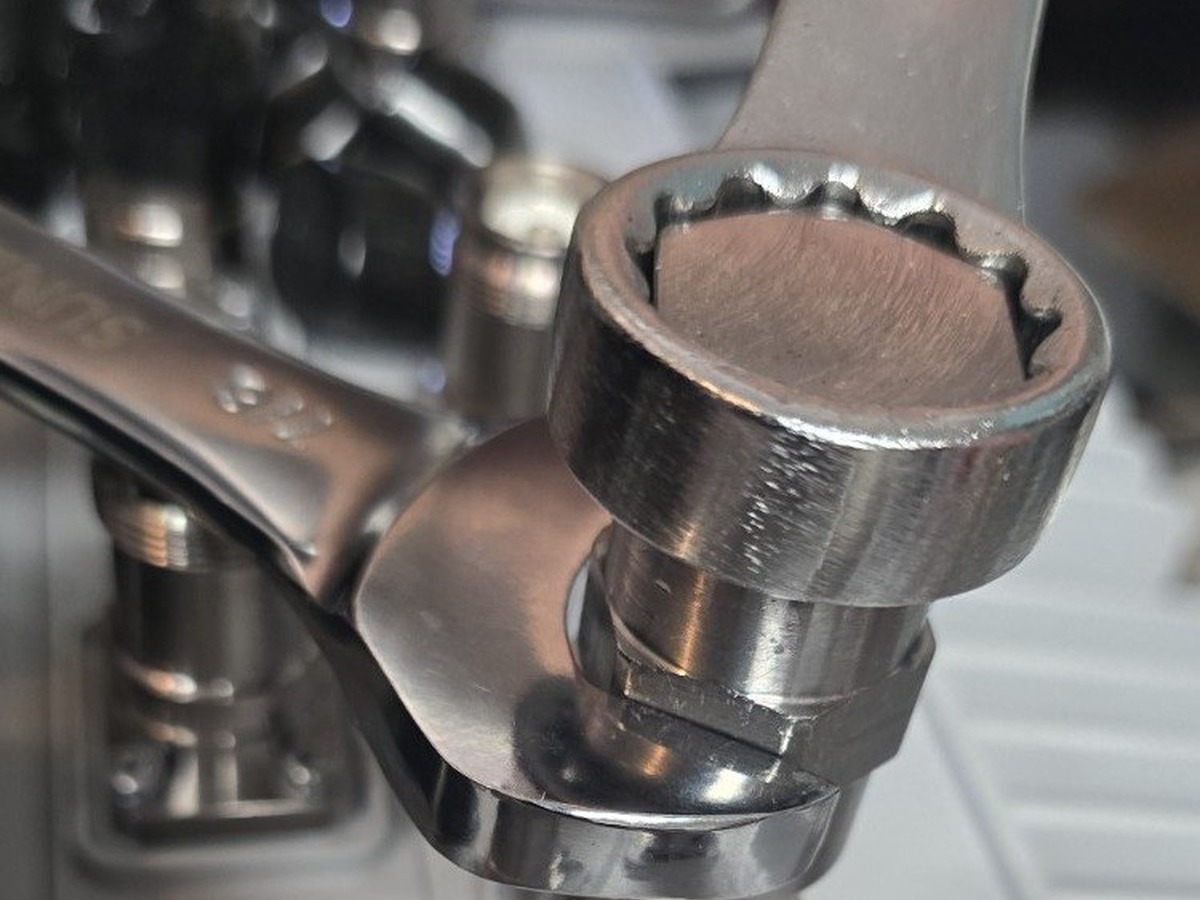 Using two wrenches to hold the guide collar and turn the mandrel